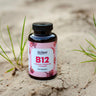 KI-generierte Abbildung (beispielhaft): Yes Vegan Vitamin B12 Kapseln mit Folsäure, B6 und Chlorella – 180 Kapseln, im Sand