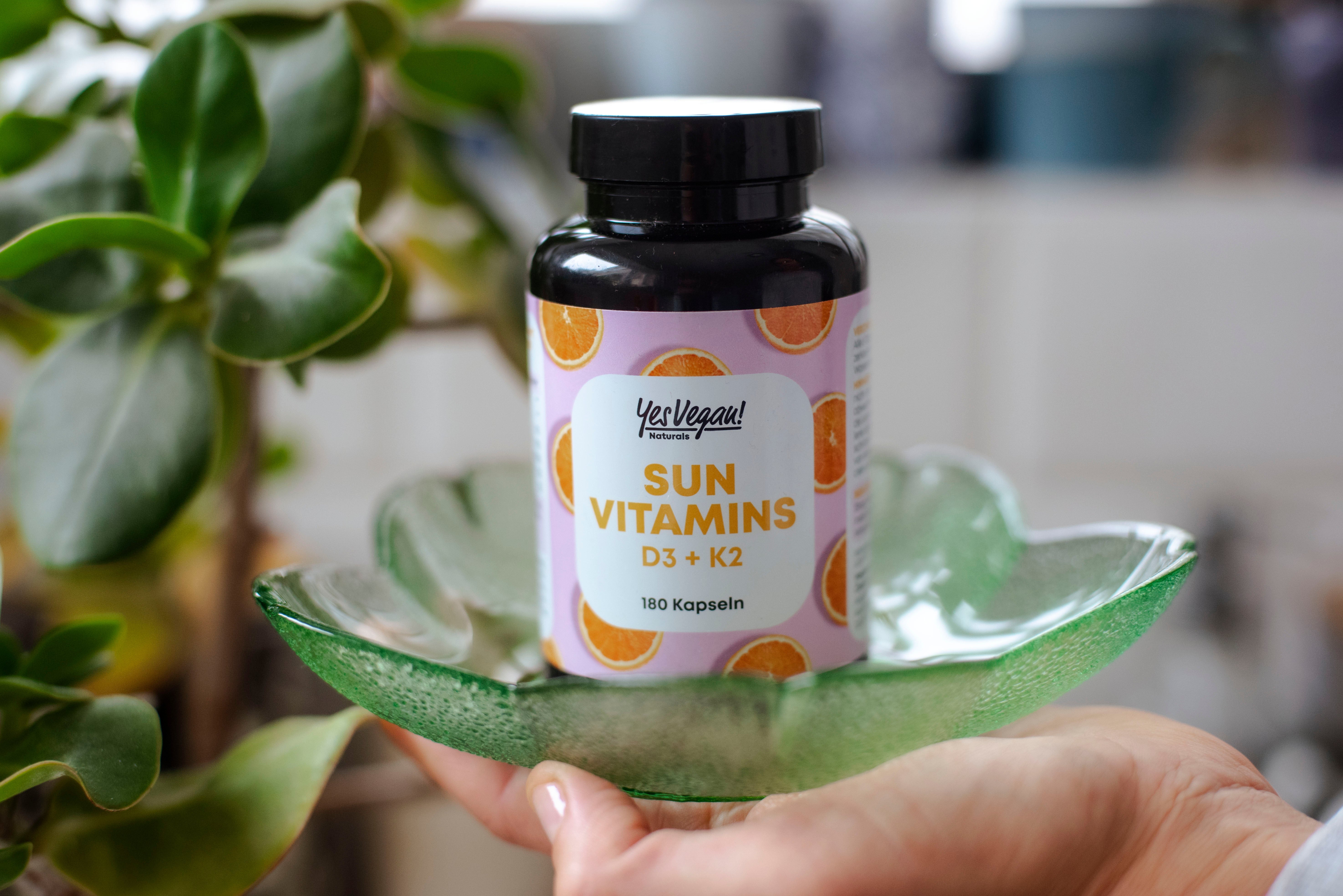 Yes Vegan Sun Vitamins D3 + K2 Dose in der Hand auf grüner Glasschale