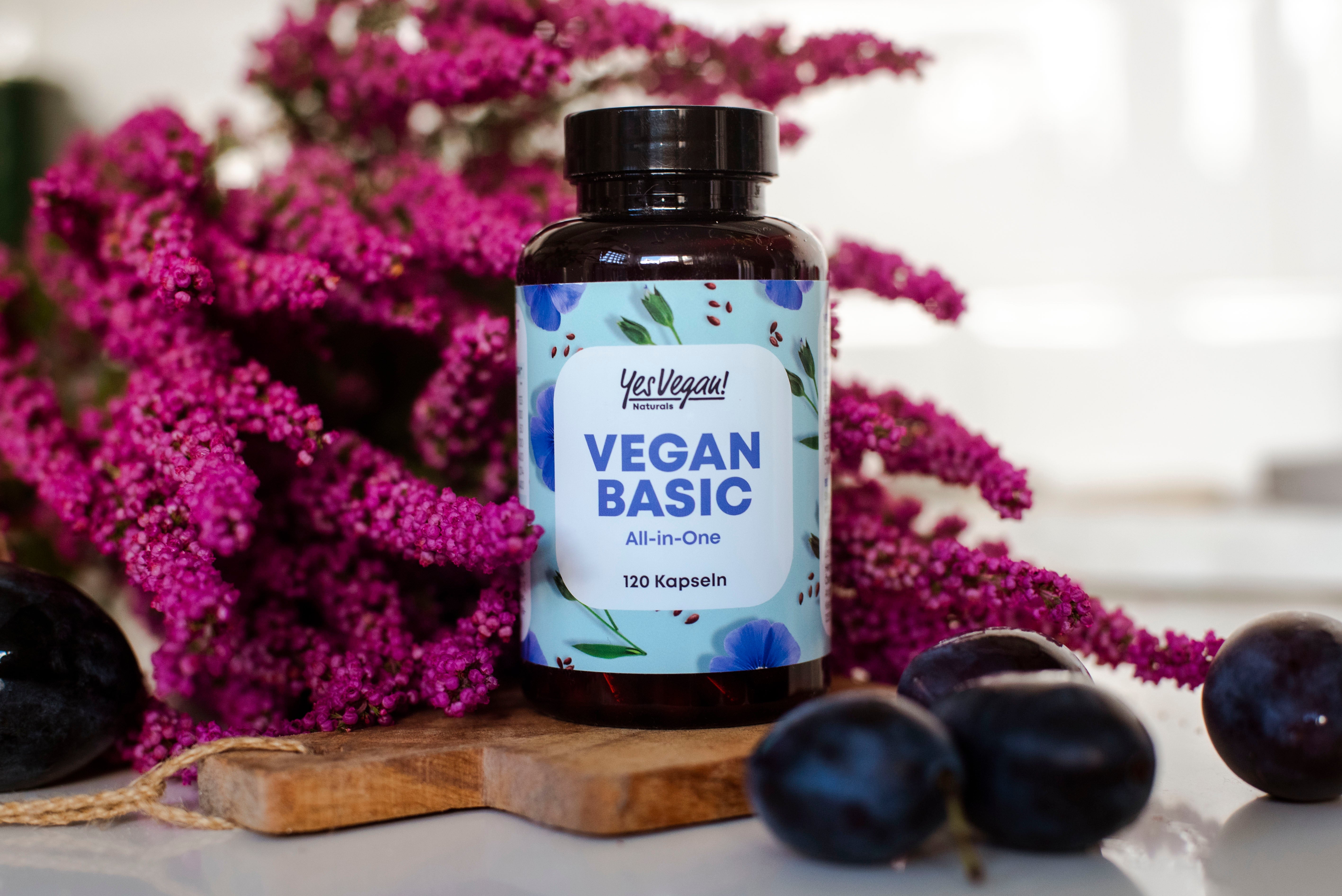 Yes Vegan Vegan Basic Dose vor lila Blüten mit Pflaumen