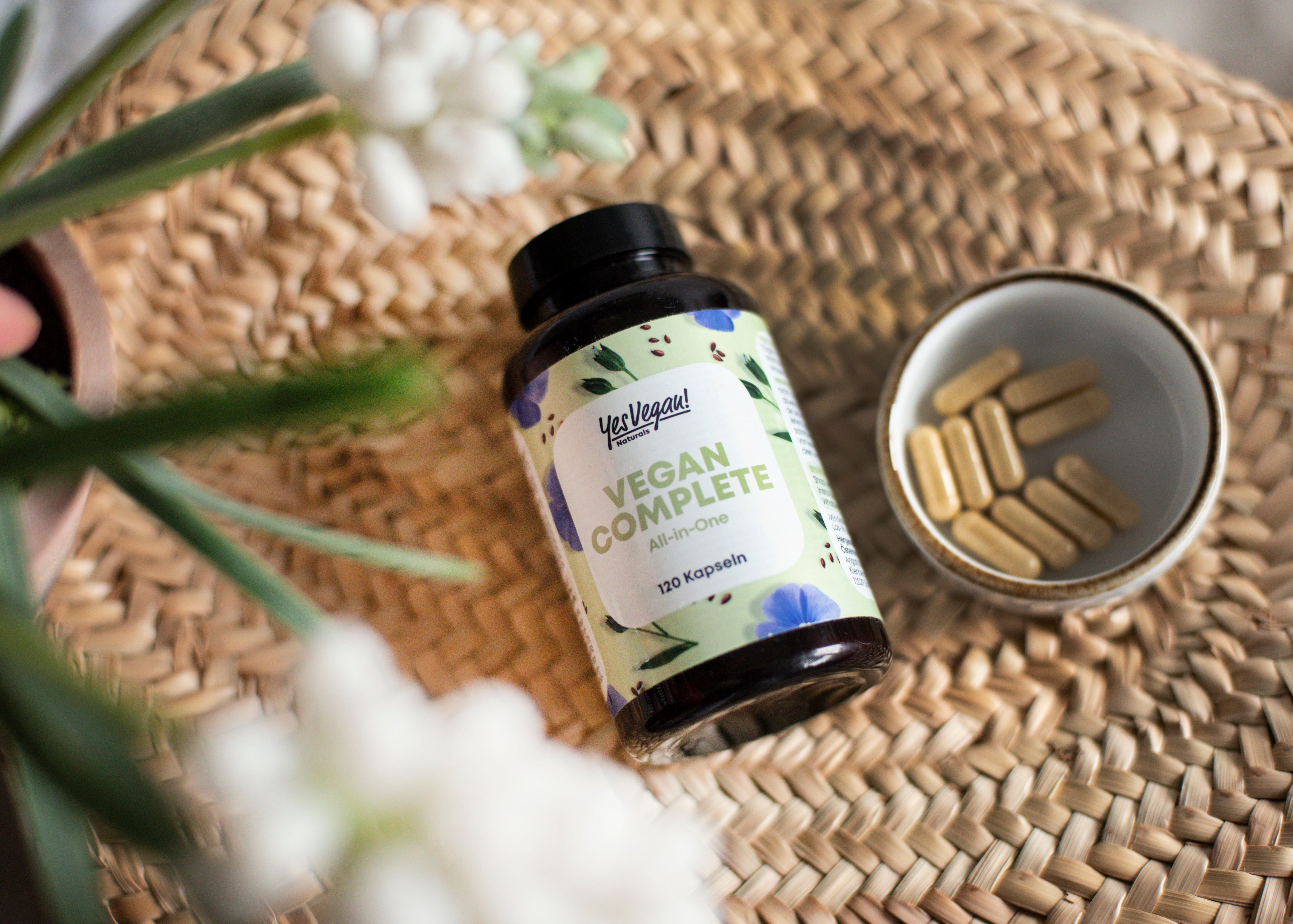 Yes Vegan Vegan Complete Dose mit Kapseln in Schale auf Korbgeflecht