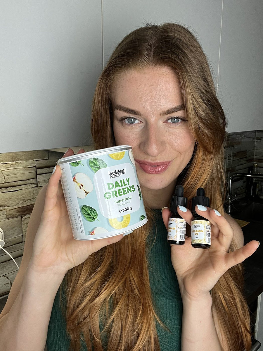 Frau mit Yes Vegan Daily Greens und Vitamin B12 und D3 Tropfen in der Küche