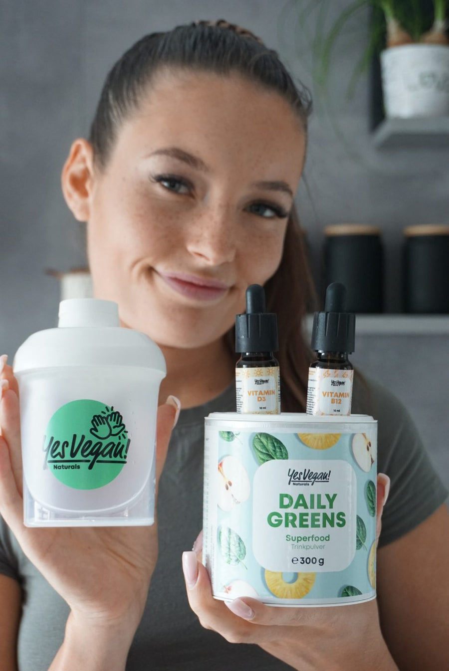 Frau mit Yes Vegan Shaker, Daily Greens und Vitamintropfen